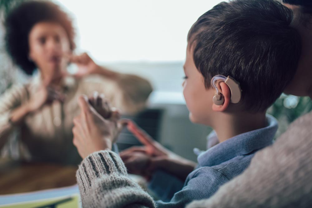 Deaf boy learning sign language with parent and teacher