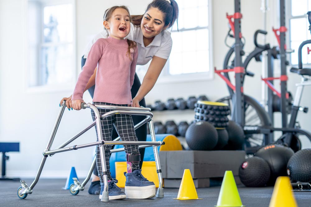 A little girl with a limb difference and a leg brace works with her physical therapist